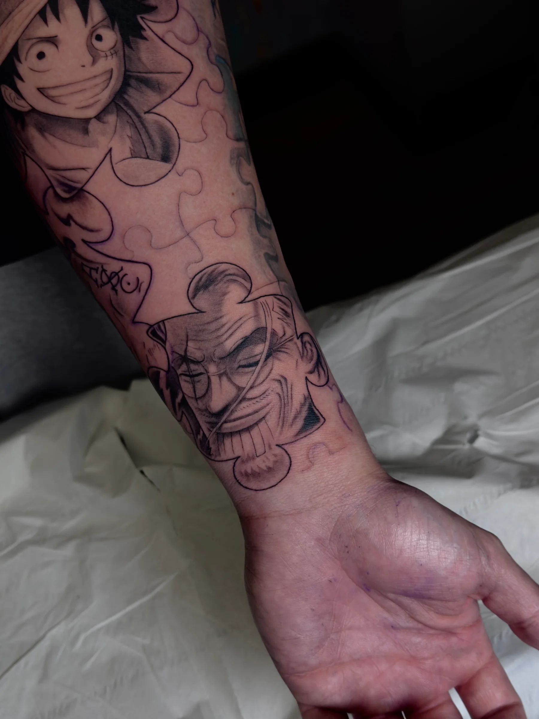 Luffy and another One Piece character over a puzzle, on the forearm
