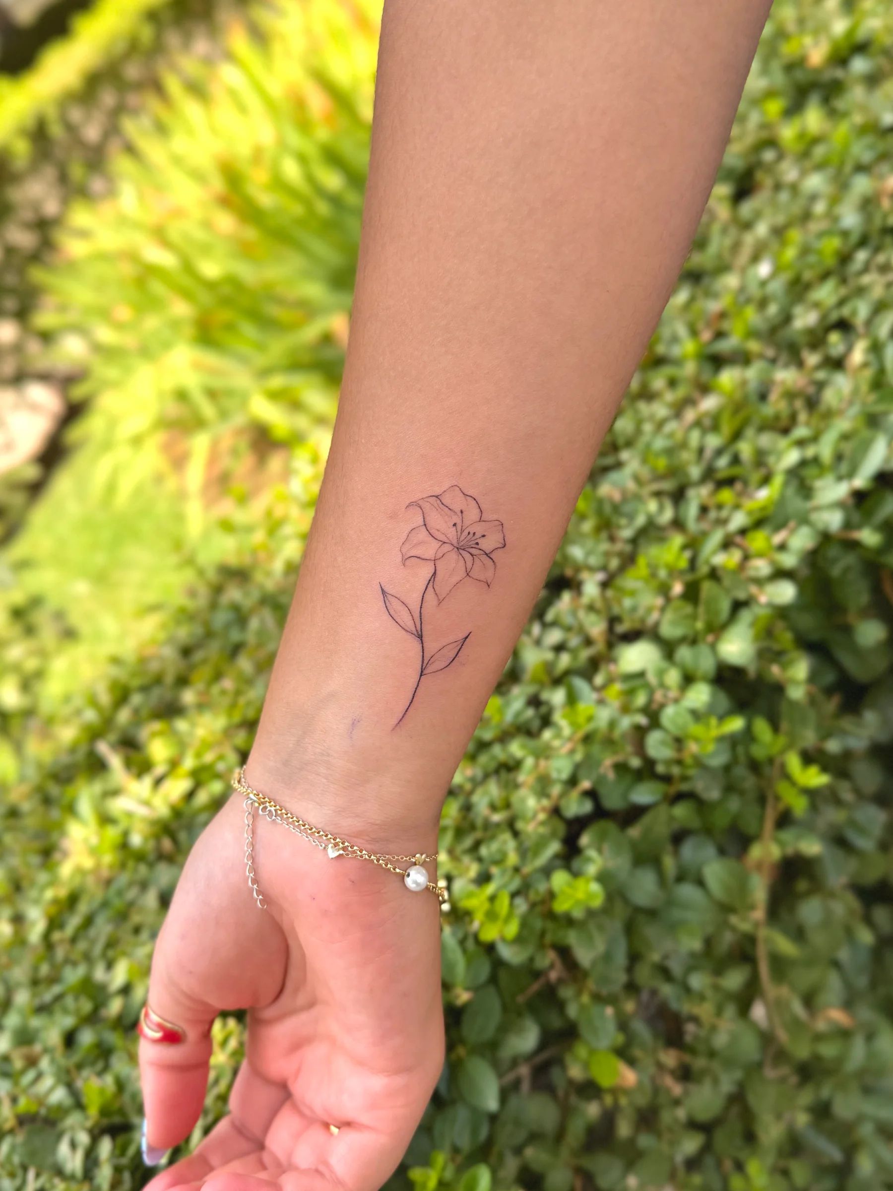 Fine line flower on the forearm, near the wrist