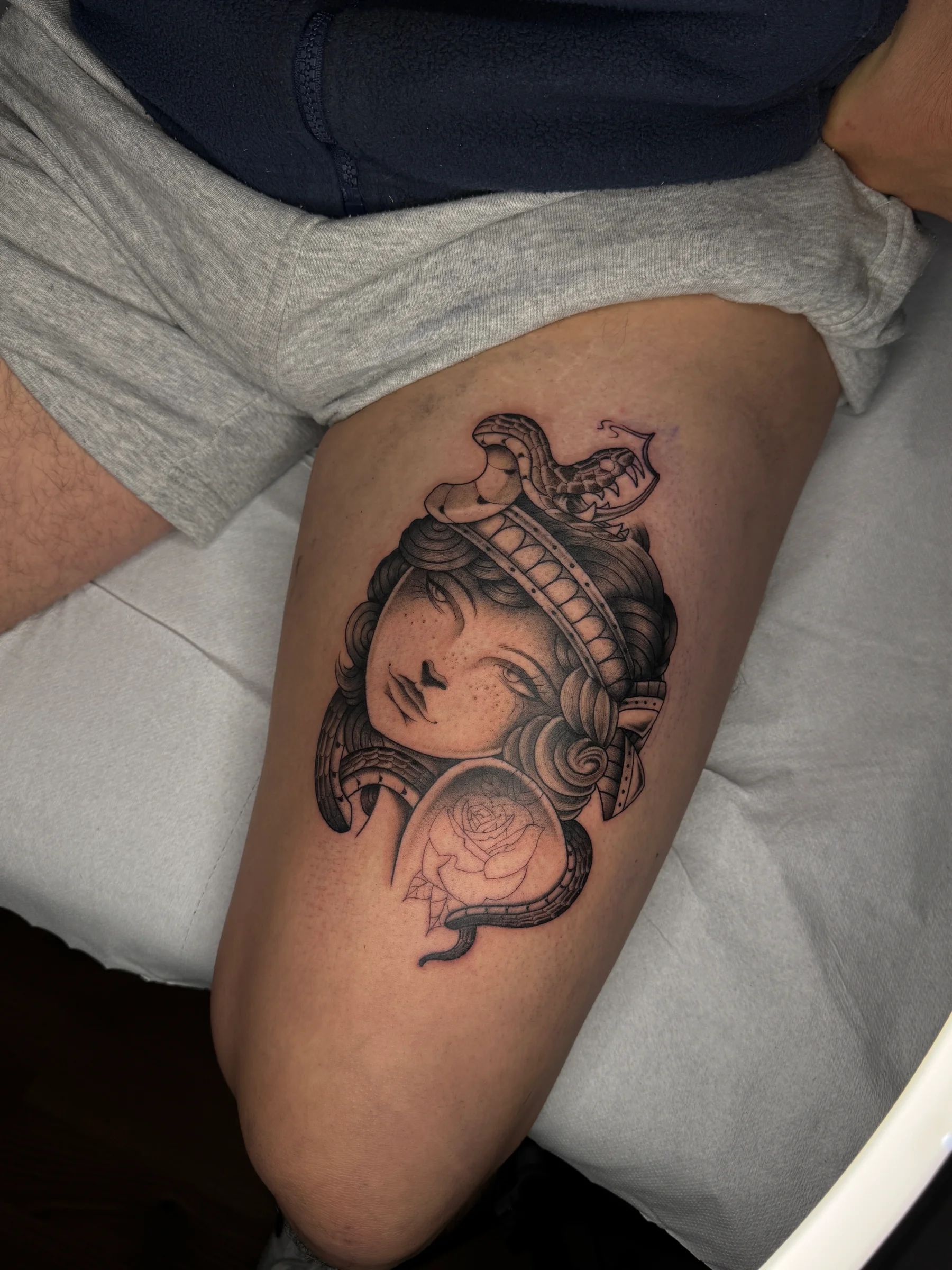 Woman's head with a snake and a rose on the thigh