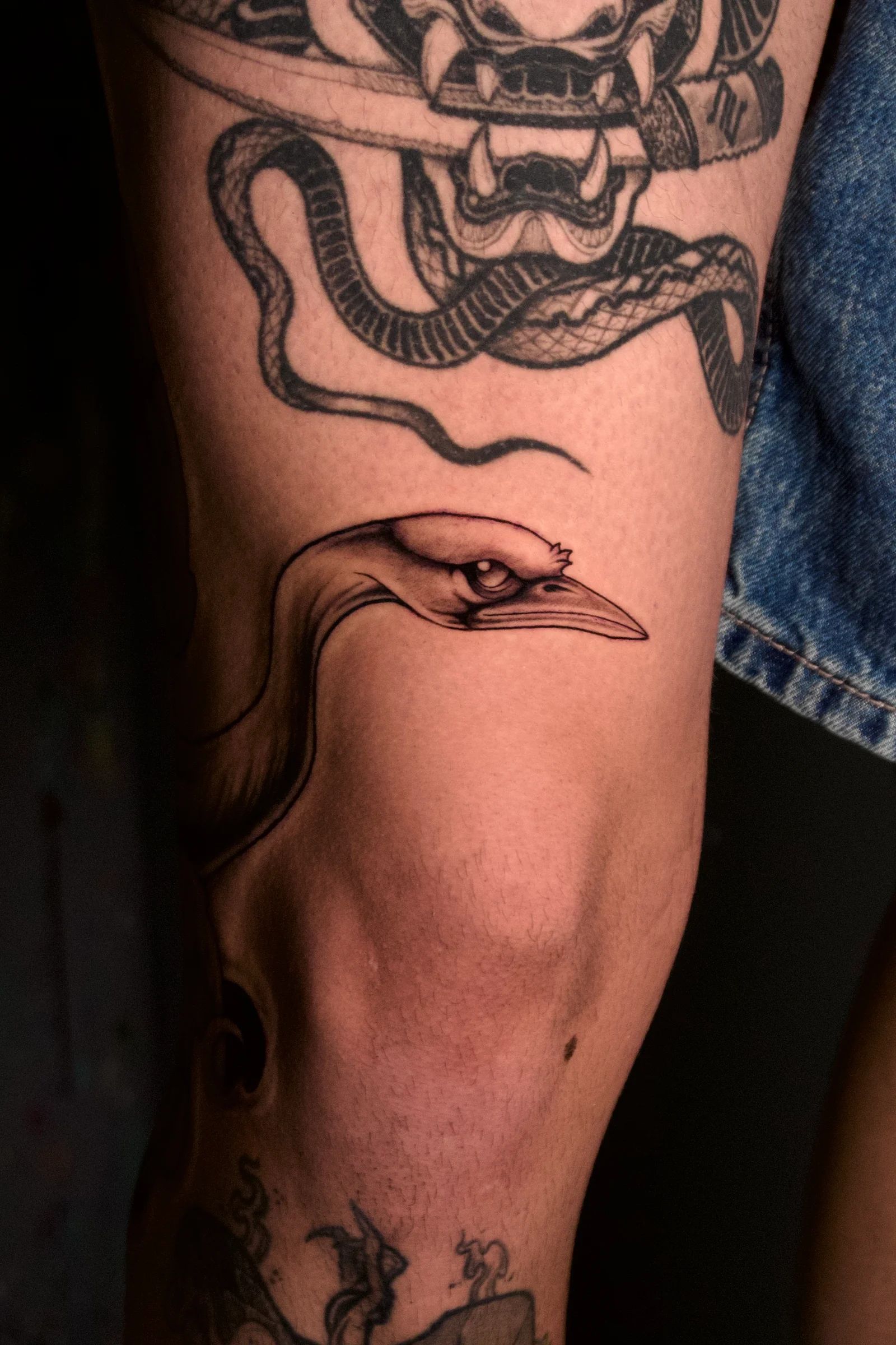 Heron head above the knee, under a snake and a mask
