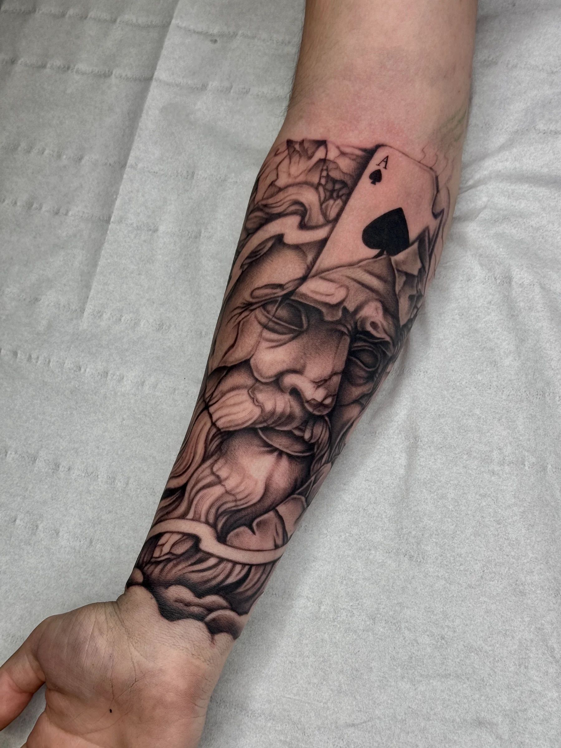 Statue face with an ace of spades on the forearm